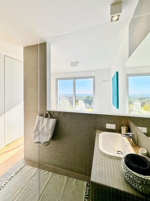 Un baño moderno con un ventanal grande, una bañera y un perchero para toallas.