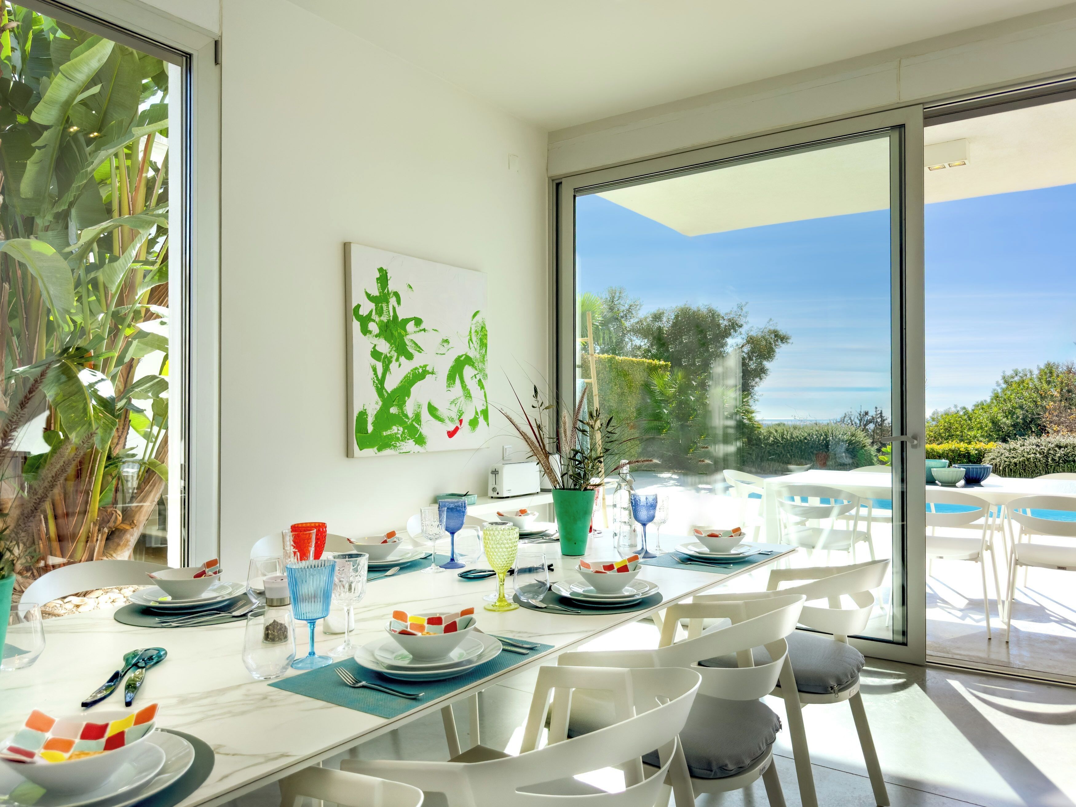 Un comedor con una mesa dispuesta para cuatro, ventanas amplias y vistas al exterior.