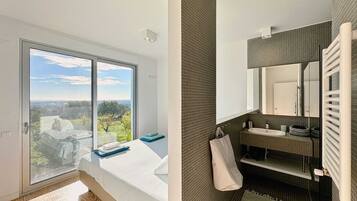 Un dormitorio con un ventanal que ofrece vistas de la ciudad, una cama con cabecera azul y vistas al exterior.