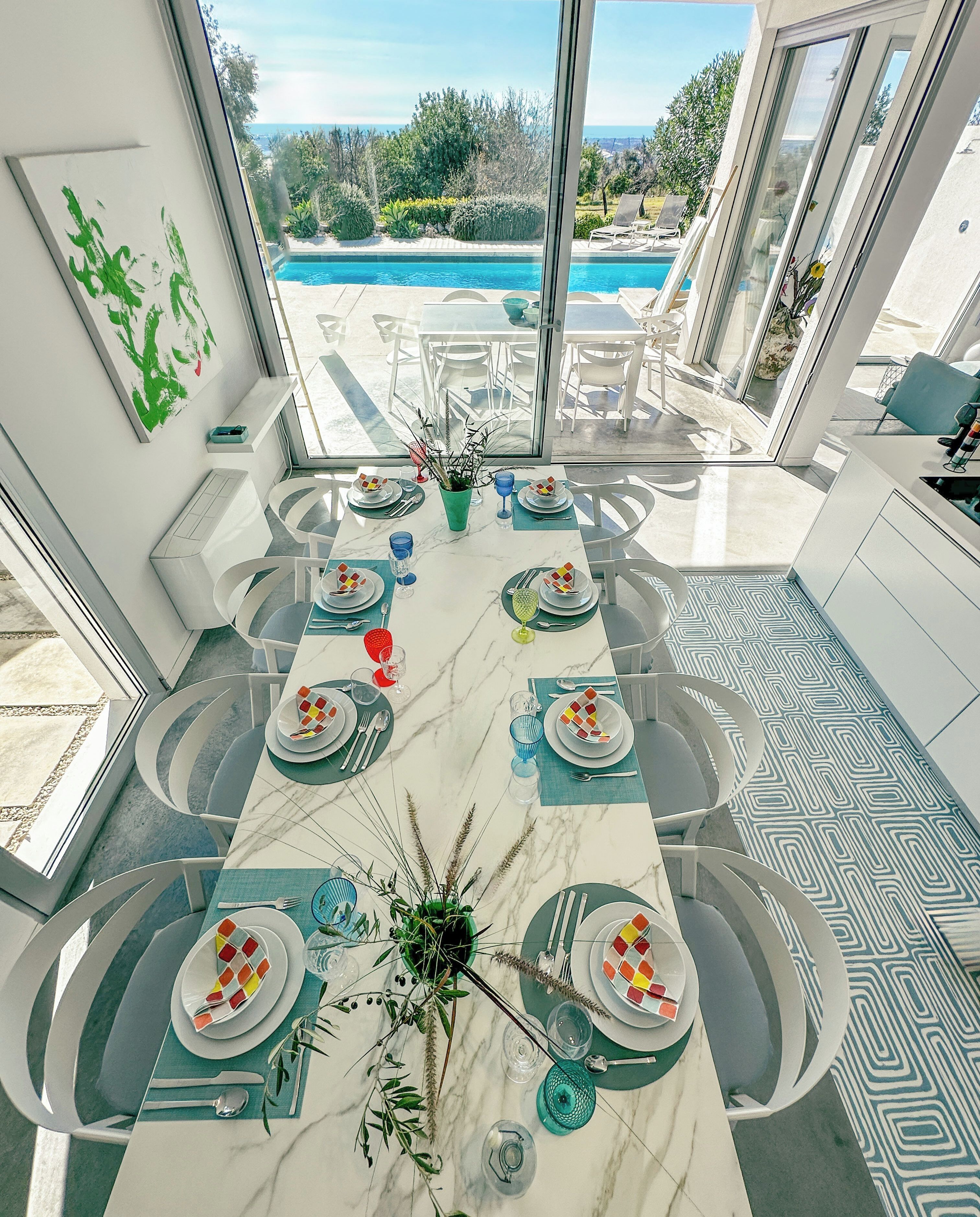 A dining area with a view of a swimming pool and a patio with lounge chairs.