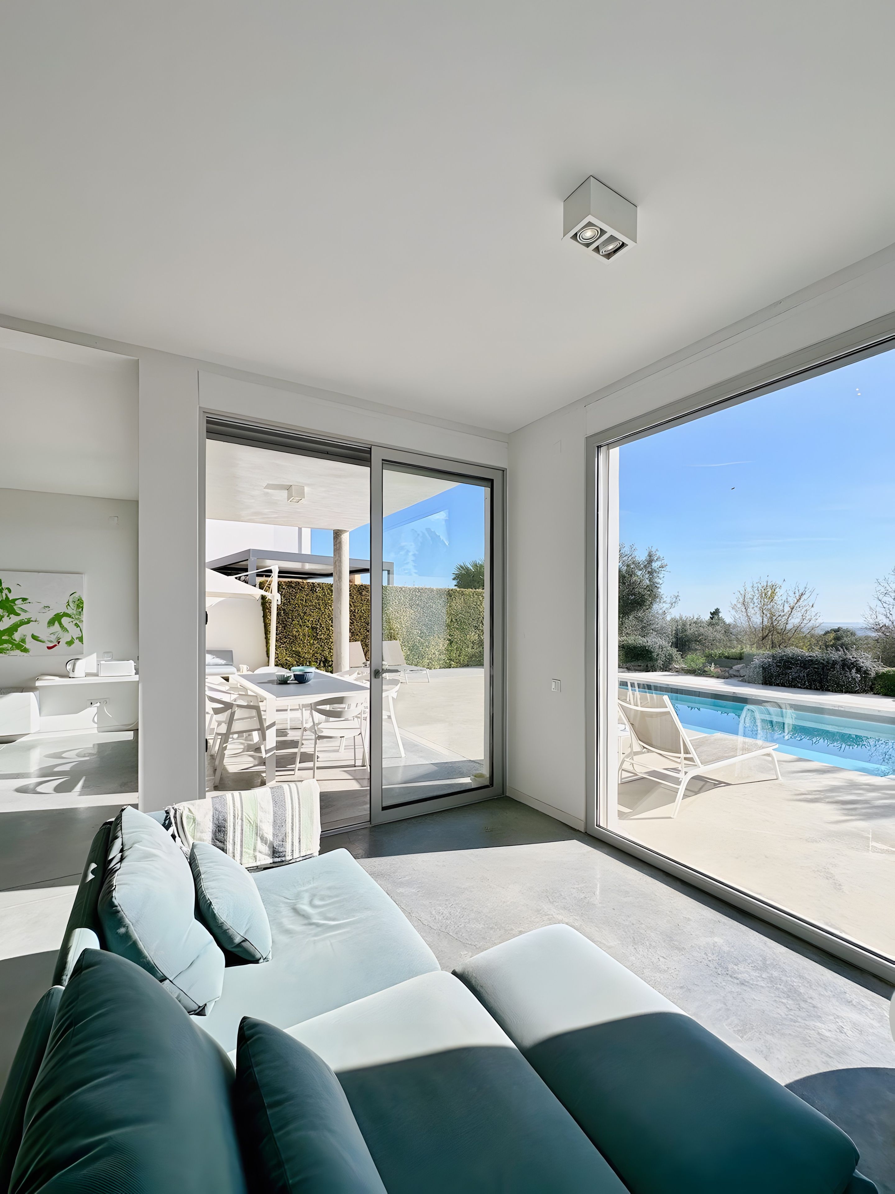 A modern living room with a large sliding glass door leading to an outdoor area with a pool.