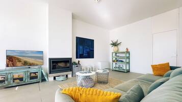 A modern living room with a flat-screen TV, a fireplace, a sofa, and a coffee table.