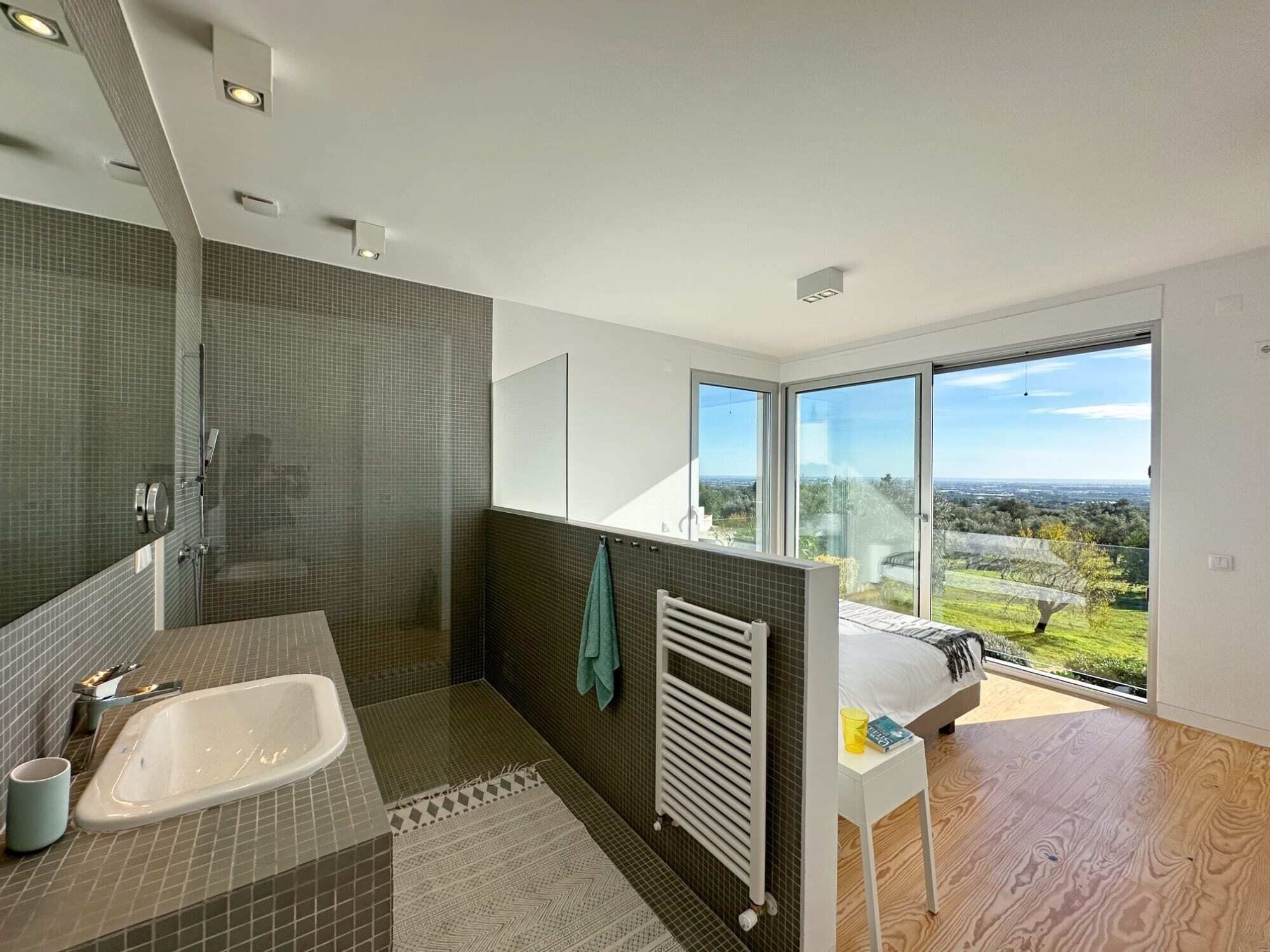 Un baño moderno con bañera, ducha y ventanas amplias que ofrecen vistas al exterior.