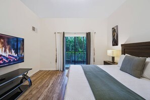 Camera d'albergo con un letto, una televisione, un comodino, una lampada e vista sull'esterno.