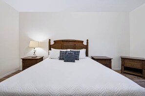 A neatly made bed with a wooden headboard, a bedside lamp, and a nightstand with a drawer. - Amazing 3BR at Caribbean Cove Resort Near Disney (Kissimmee)
