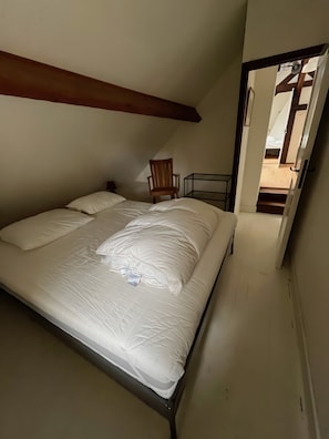 A bedroom with a bed, a chair, and a staircase leading to an upper level. - Holiday Home 'La Colline' with Private Terrace, Wi-Fi and Air Conditioning (Lanty)