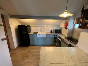 Een kleine keuken met een koelkast, magnetron, spoelbak en kastjes.