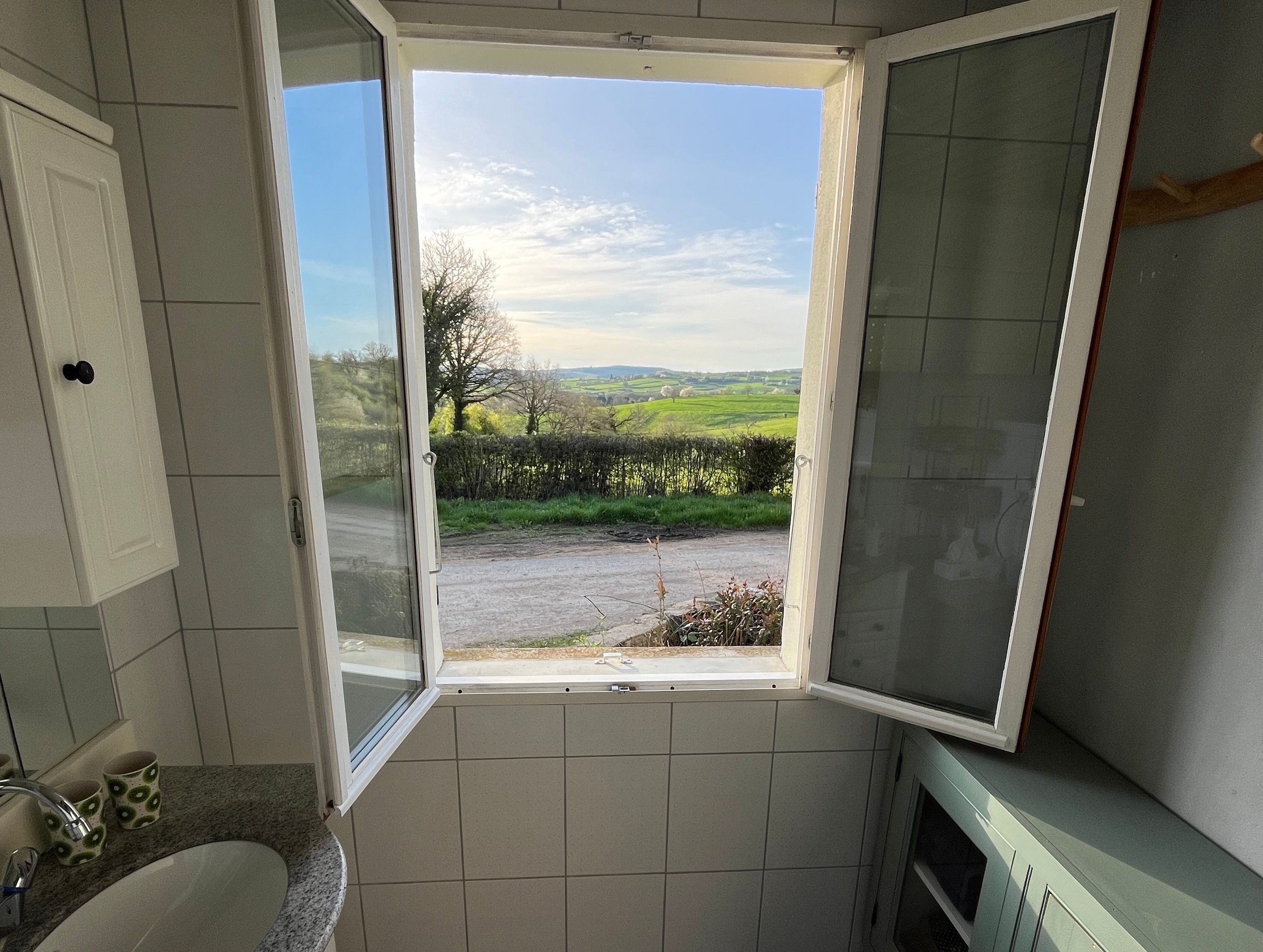 Un baño con ventana, lavamanos y espejo.