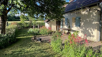 Een huis met een tuin, een bank en een boom.