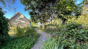 Camí al jardí que condueix a un edifici amb teulada inclinada i una finestra petita.
