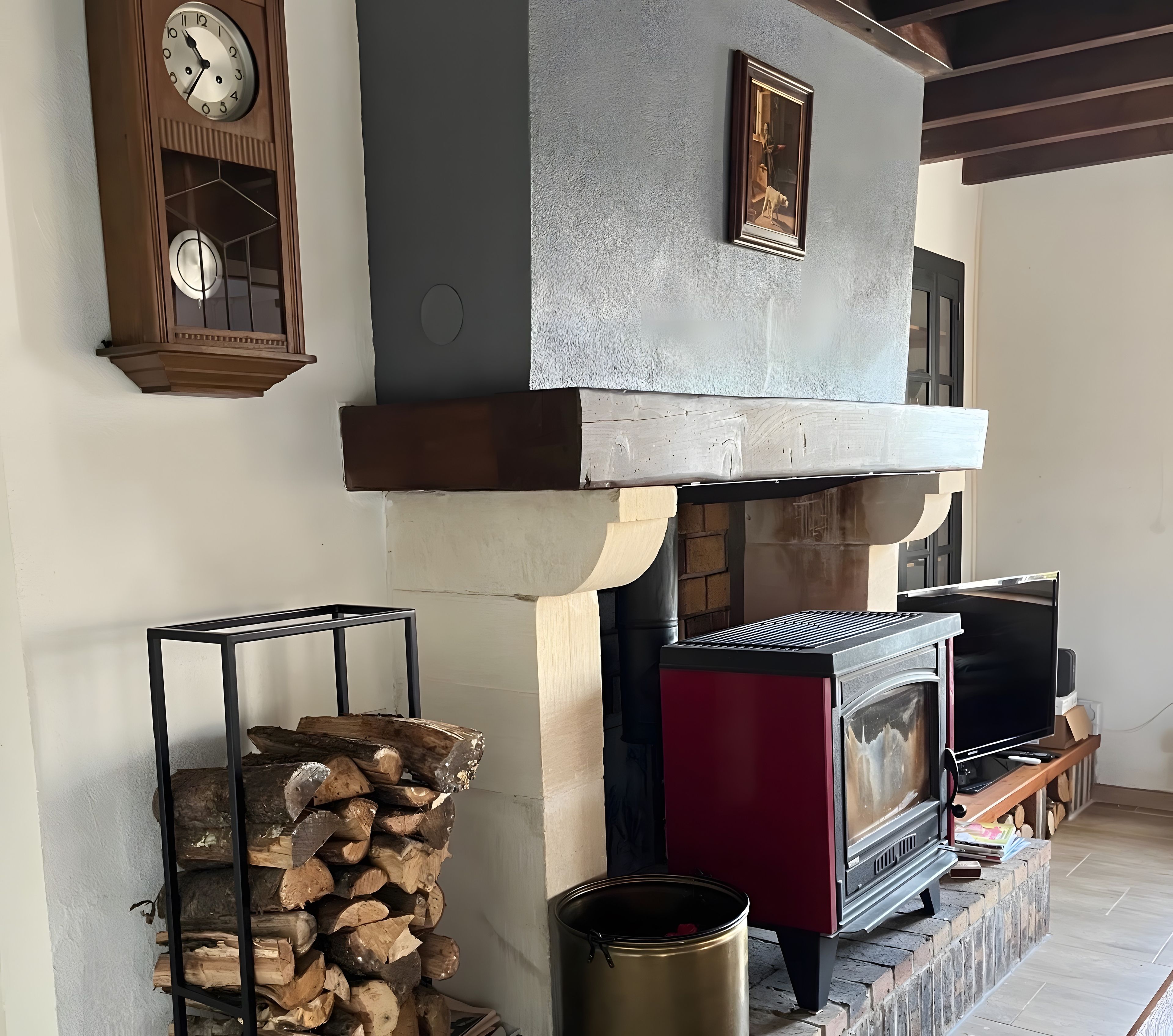 Une cheminée au design moderne, une horloge et un tableau encadré au mur.