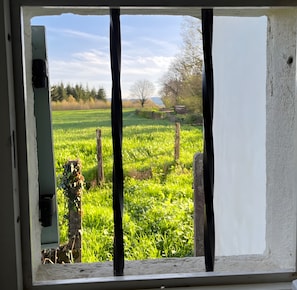 A window with a view of a green field and a tree. - Holiday Home 'La Colline' with Private Terrace, Wi-Fi and Air Conditioning (Lanty)