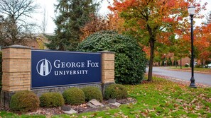 Placa da Universidade George Fox, com base de tijolos e fundo azul escuro.