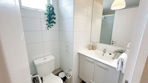 Un baño moderno con inodoro, lavamanos y espejo.