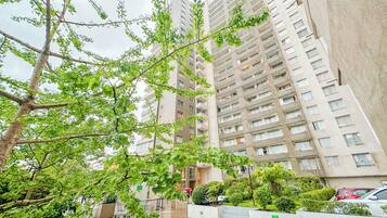 Un edificio residencial alto con varios balcones, una entrada protegida por un muro y un jardín bien cuidado.