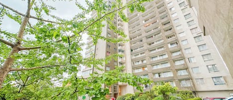 A high-rise residential building with multiple balconies, a gated entrance, and a well-maintained garden area.