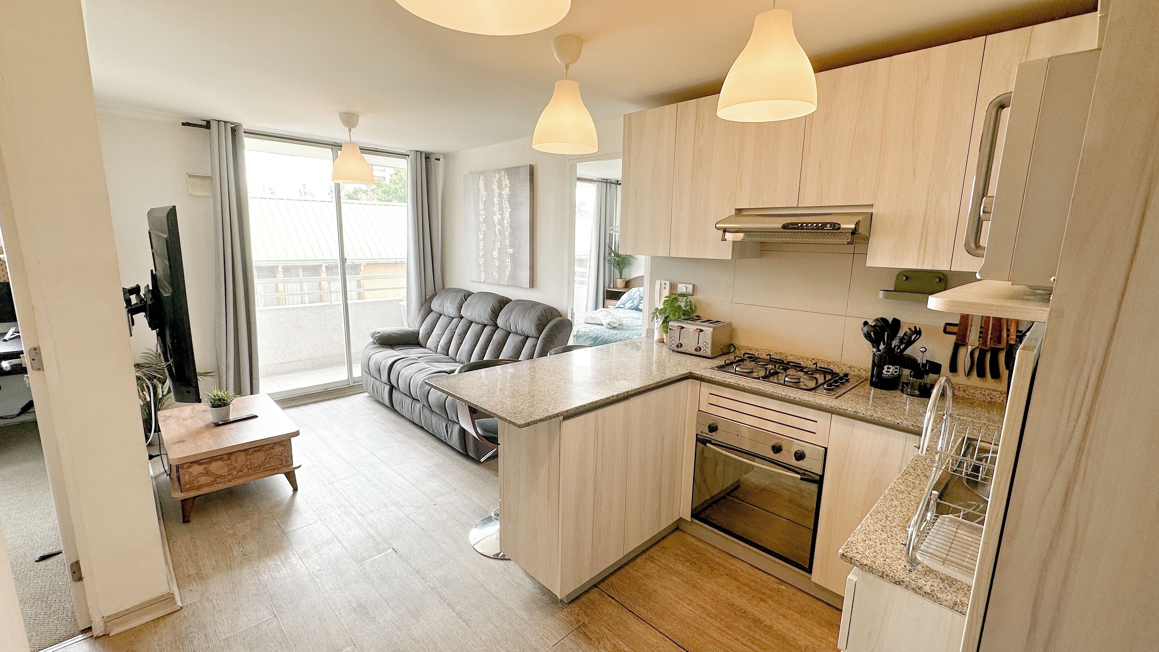 A modern kitchen with a central island, built-in oven, and a dining area with a sofa.
