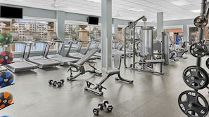 Ein Fitnessstudio mit Laufbändern, Kraftgeräten und Kurzhanteln.