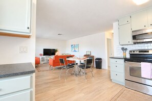 A modern kitchen with a dining area, a TV, and a microwave. - Downtown Venice Island | private patio, walkable (Venice)
