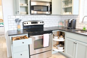 A modern kitchen with a stainless steel stove, oven, and microwave, light-colored cabinets, and a black countertop. - Downtown Venice Island | private patio, walkable (Venice)
