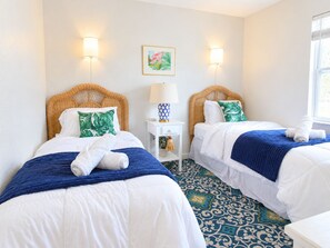 A hotel room with two beds, each with a blue and white duvet, a patterned floor, and wall-mounted lamps. - Downtown Venice Island | private patio, walkable (Venice)