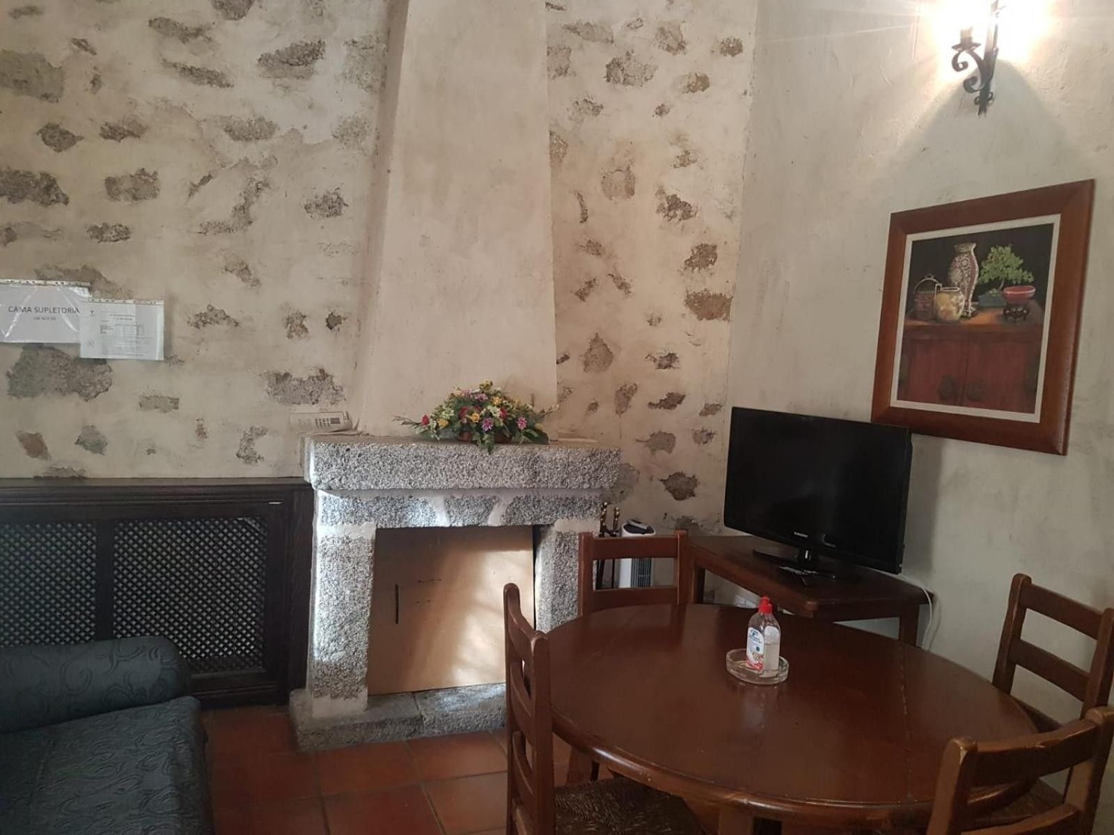 Una habitación con chimenea de piedra, televisión, mesa de comedor con sillas y pared con diseño.