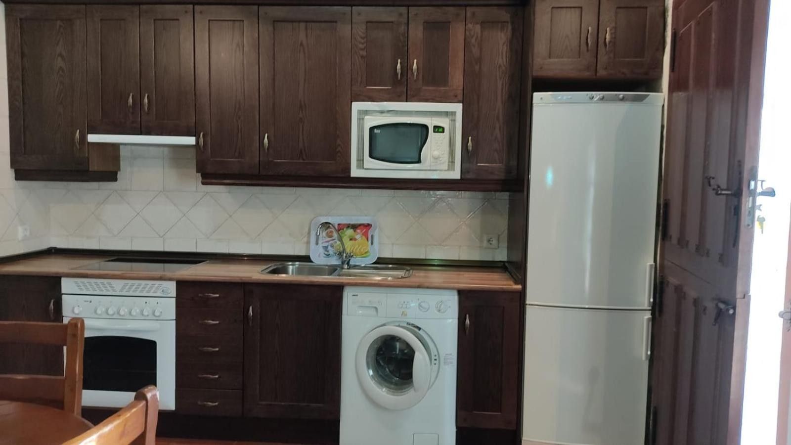 Une cuisine équipée de meubles en bois, d’un four à micro-ondes, d’un lave-vaisselle et d’une machine à laver.