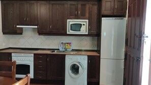 A kitchen with wooden cabinets, a microwave, a dishwasher, and a washing machine.