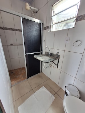 Et badeværelse med toilet, vask og bruseområde.