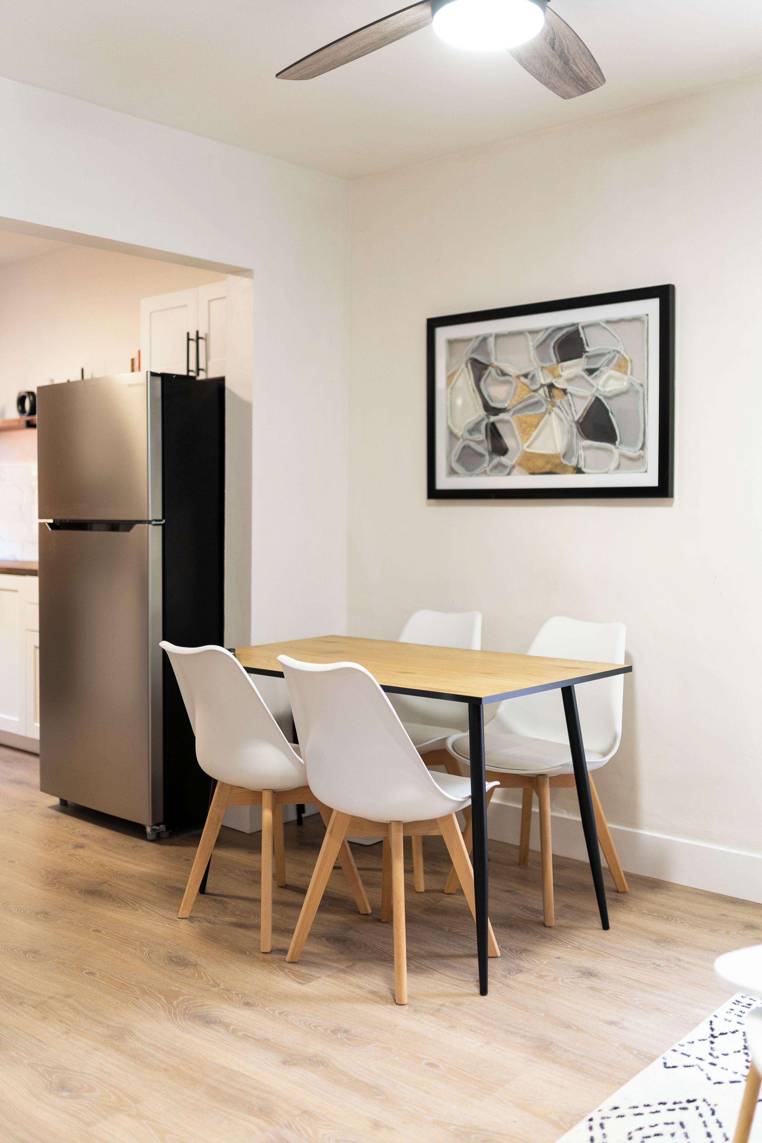 Une cuisine moderne équipée d’un réfrigérateur intégré, d’une table à manger avec quatre chaises et d’un ventilateur de plafond.
