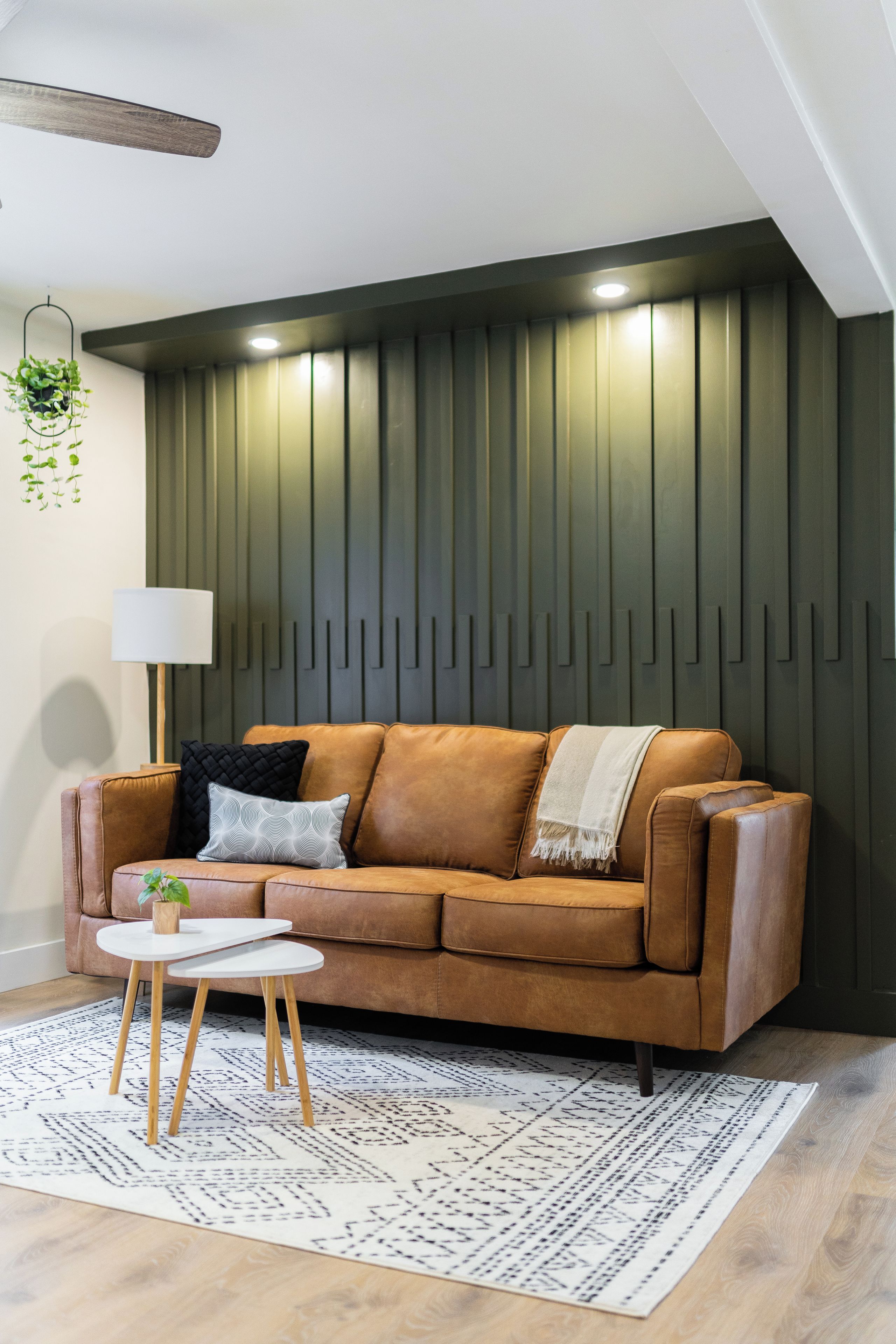 A modern living room with a brown leather sofa, a white round coffee table, and a patterned rug.