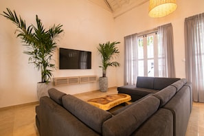 A modern living room with a grey sofa, a wooden coffee table, and two large potted plants. - Old City 11 Bedroom Mansion (Cartagena de Indias)