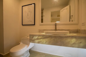 A bathroom with a toilet, a sink with a marble countertop, and a framed artwork on the wall. - Old City 11 Bedroom Mansion (Cartagena de Indias)