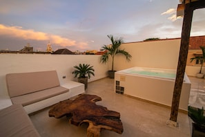 A rooftop terrace with a sofa, a wooden coffee table, a hot tub, and a view of a city skyline. - Old City 11 Bedroom Mansion (Cartagena de Indias)