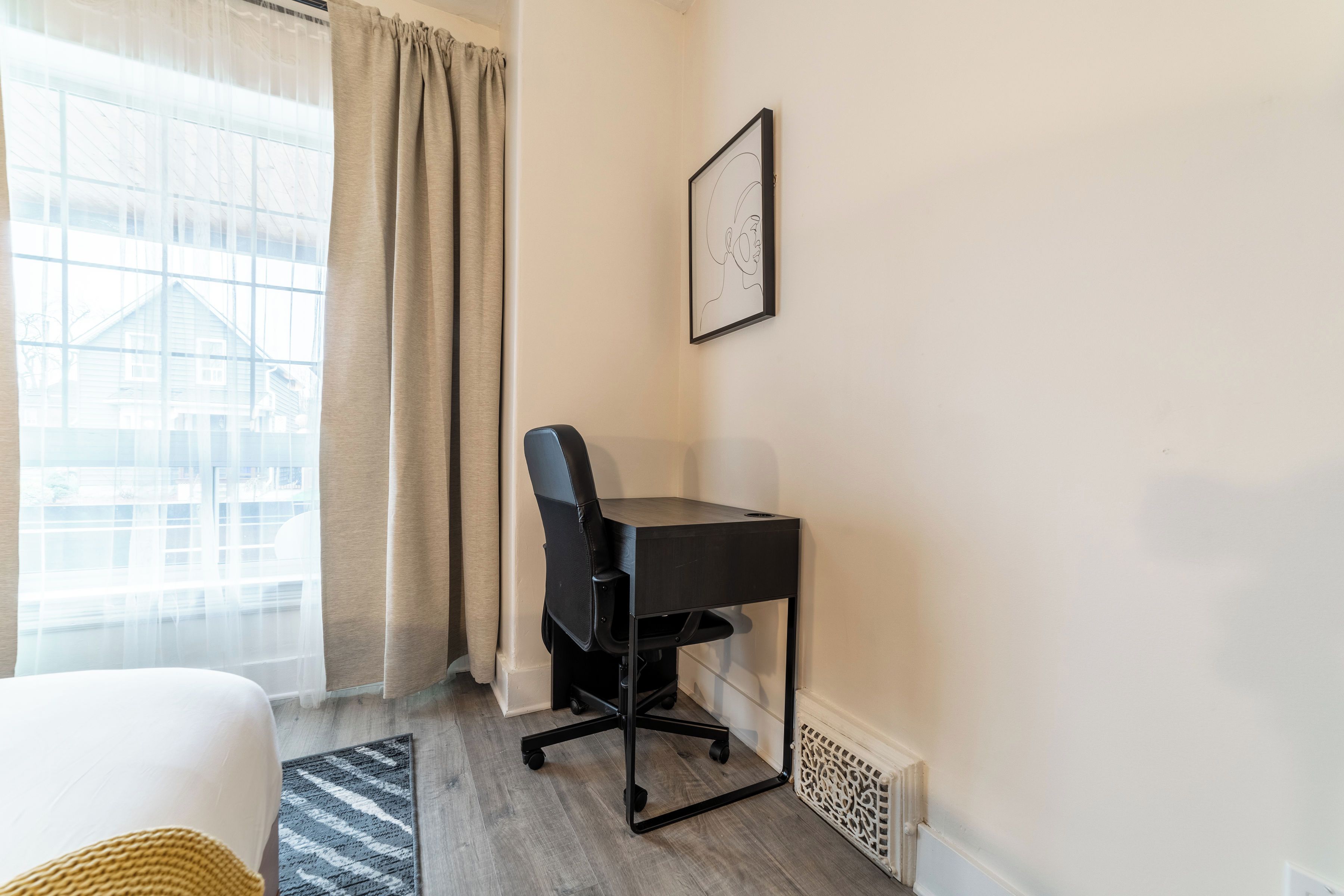 Une pièce comprenant un bureau, une chaise et une fenêtre avec des rideaux.