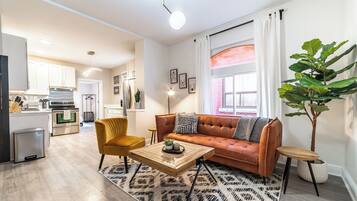 A modern living room with a sofa, coffee table, and a large plant.