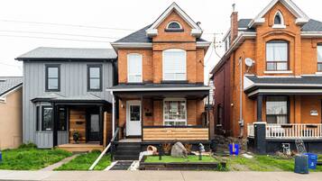 A row of three houses with distinct architectural styles, a front yard, and a sidewalk.