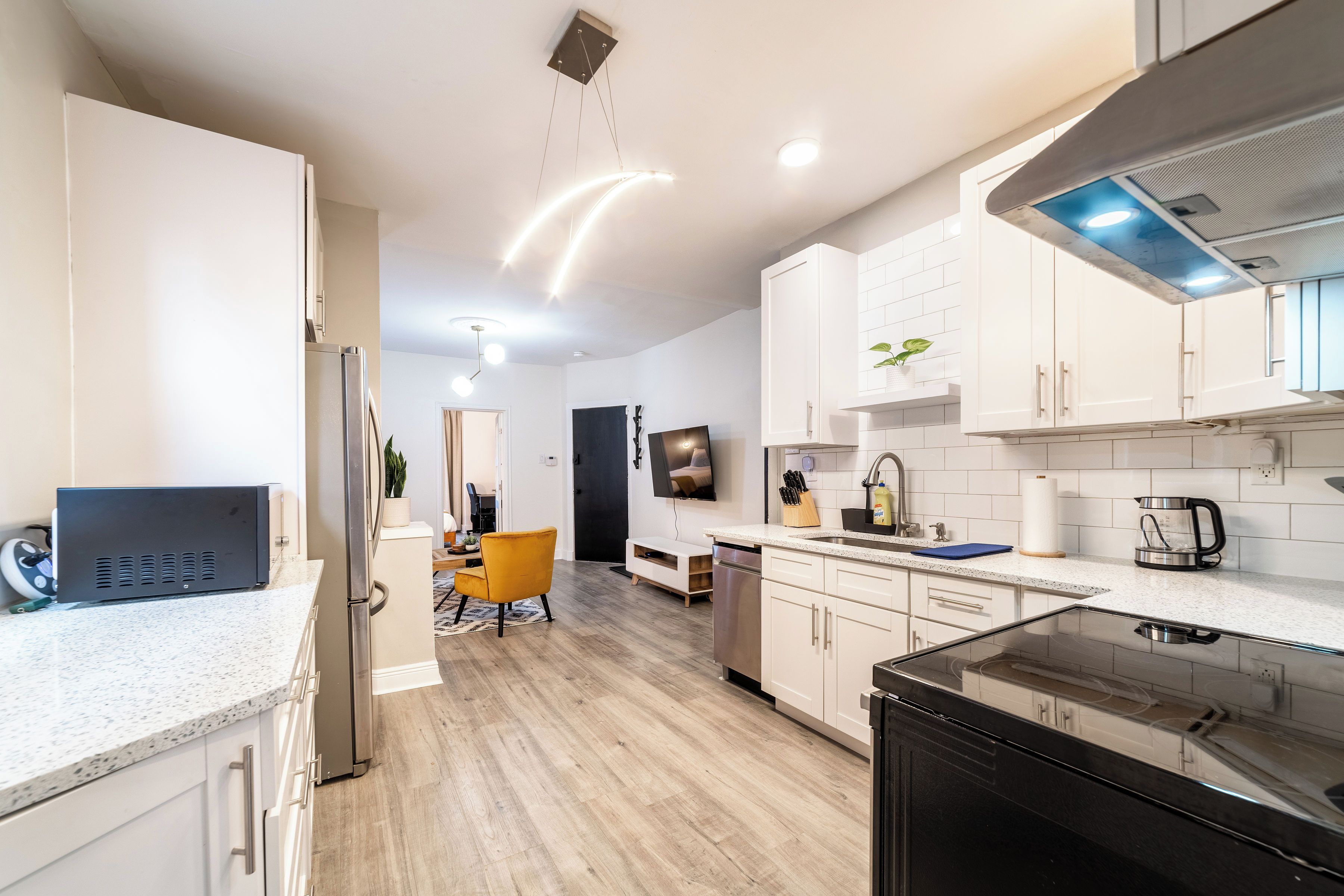 A modern kitchen with white cabinetry, a black refrigerator, and a stainless steel range hood.
