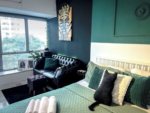 A bedroom with a bed, a black leather sofa, a green quilted bedspread, and a window with blinds. - The Photographer Loft - Unique and spacious flat in the center of Rio (Rio de Janeiro)