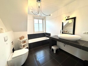Ein modernes Badezimmer mit Toilette, Badewanne und Waschbecken.