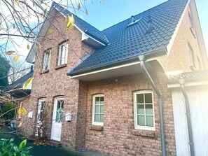 Ein zweistöckiges Backsteinhaus mit geneigtem Dach und einem sichtbaren Schornstein.