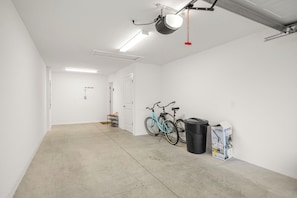 A clean, empty garage with white walls, a concrete floor, and a ceiling-mounted light fixture. - 2BR · 2 Bath · Golf Cart · Mins to Eastport Sq (Sumterville)