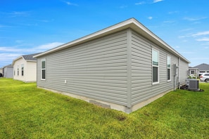 A single-story residential building with a flat roof, a central door, and a small attached garage. - 2BR · 2 Bath · Golf Cart · Mins to Eastport Sq (Sumterville)
