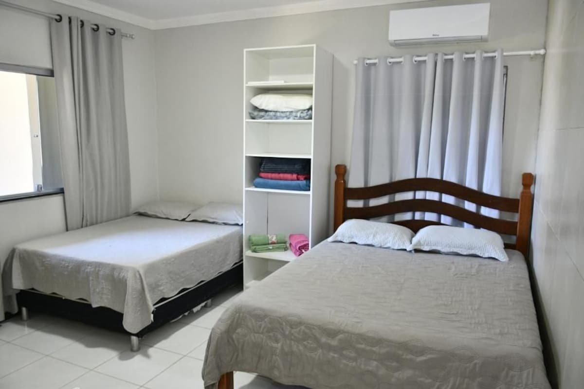 A room with two beds, a wardrobe, and an air conditioning unit.