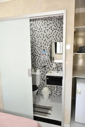 A bathroom with a tiled wall, a toilet, a sink, and a mirror. - Pousada Bem-Te-Vi (Aracaju)