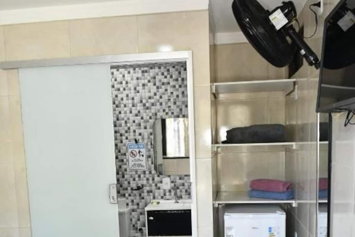 A small room with a bed, a refrigerator, a microwave, and a sink.
