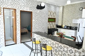 A kitchen with a tiled backsplash, a refrigerator, and a bar area with stools. - Pousada Bem-Te-Vi (Aracaju)