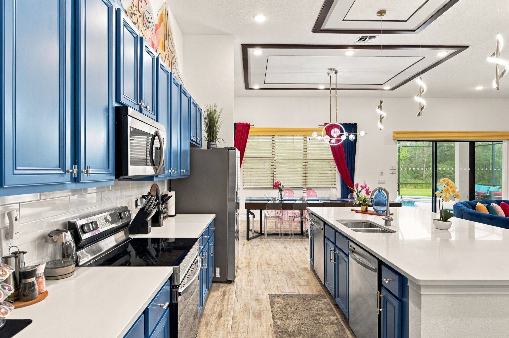 A modern kitchen with blue cabinets, stainless steel appliances, and a large island with a sink.