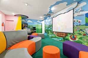 Ein Spielzimmer für Kinder mit farbigem Möbel, einem großen Wandgemälde und einem Fernsehbildschirm.