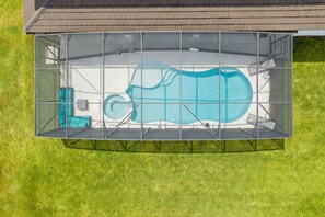 Ein Swimmingpool mit Glasveranda, umgeben von einer Rasenfläche.